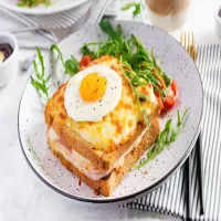 Croque Madame: chrupiący francuski tost z beszamelem, dojrzewającym serem, plastrem szynki i jakiem sadzonym